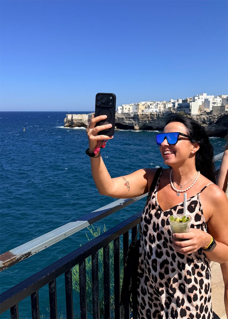 Viešnia fotografuoja Polignano a Mare vaizdą nuo terasos